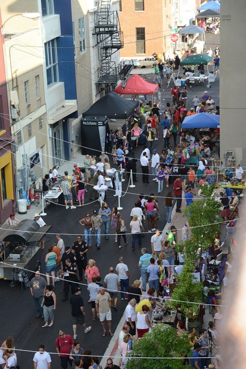 The image of the street with crowds of people shopping at stands.