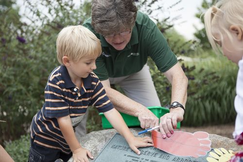 The image of a woman helping a child do crafts.