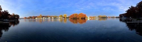 The image is of a river with trees in the distance orange, red, and yellow. 